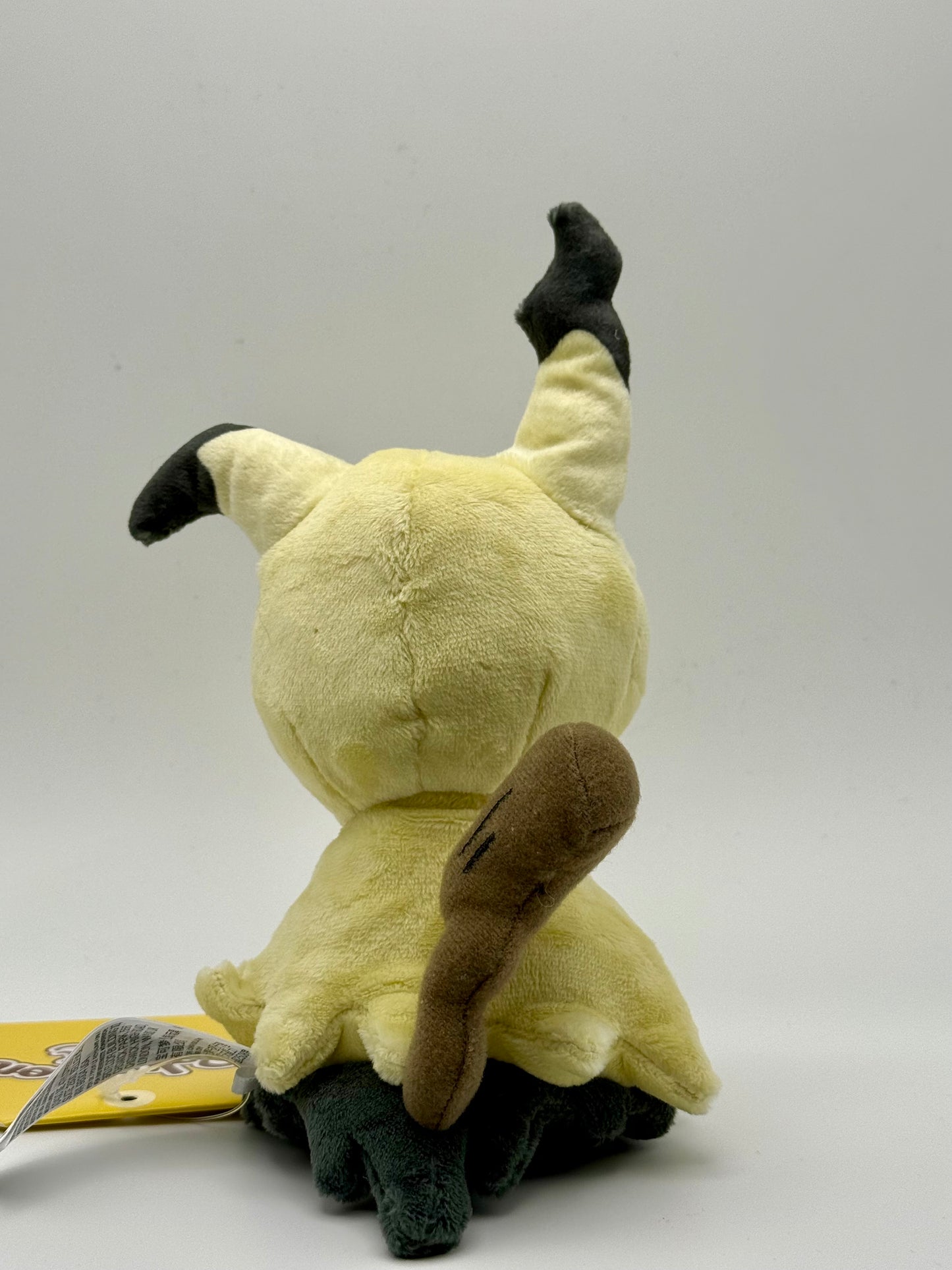 Eevolvd Mimikyu Plush med mjuk känsla sedd med baksidan i fokus direkt fran Pokemon Center Japan