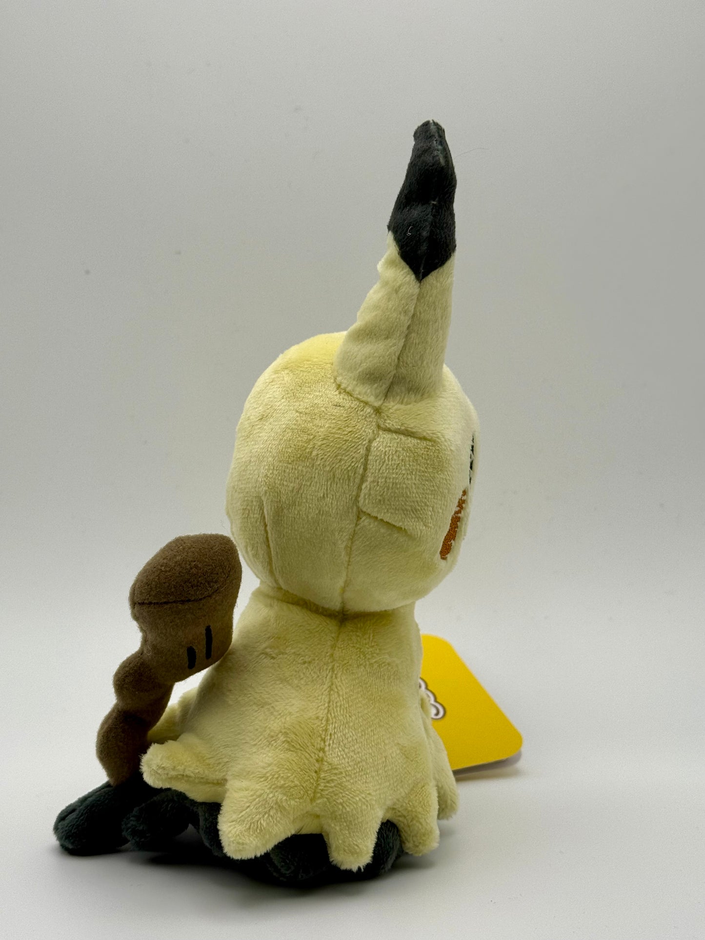 Eevolvd Mimikyu Plush med mjuk känsla sedd med vänster sidan i fokus direkt fran Pokemon Center Japan