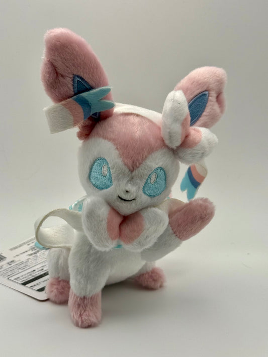 Eevolvd Sylveon Plush med vinkandes och sittandes pose sedd framifran direkt fran Pokemon Center Japan