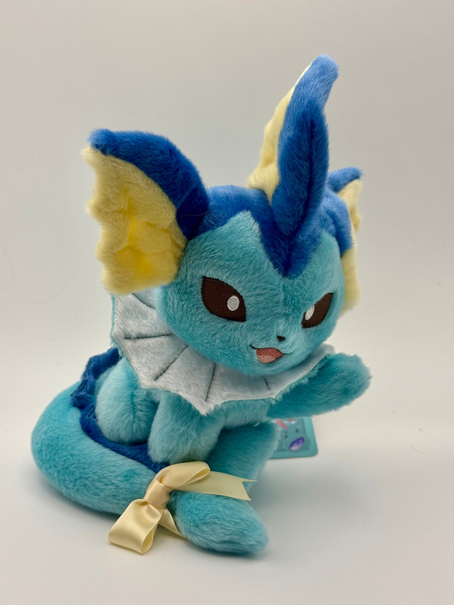 Eevolvd Vaporeon Plush med vinkande tass och sittandes med ett leende sedd framifran direkt fran Pokemon Center Japan