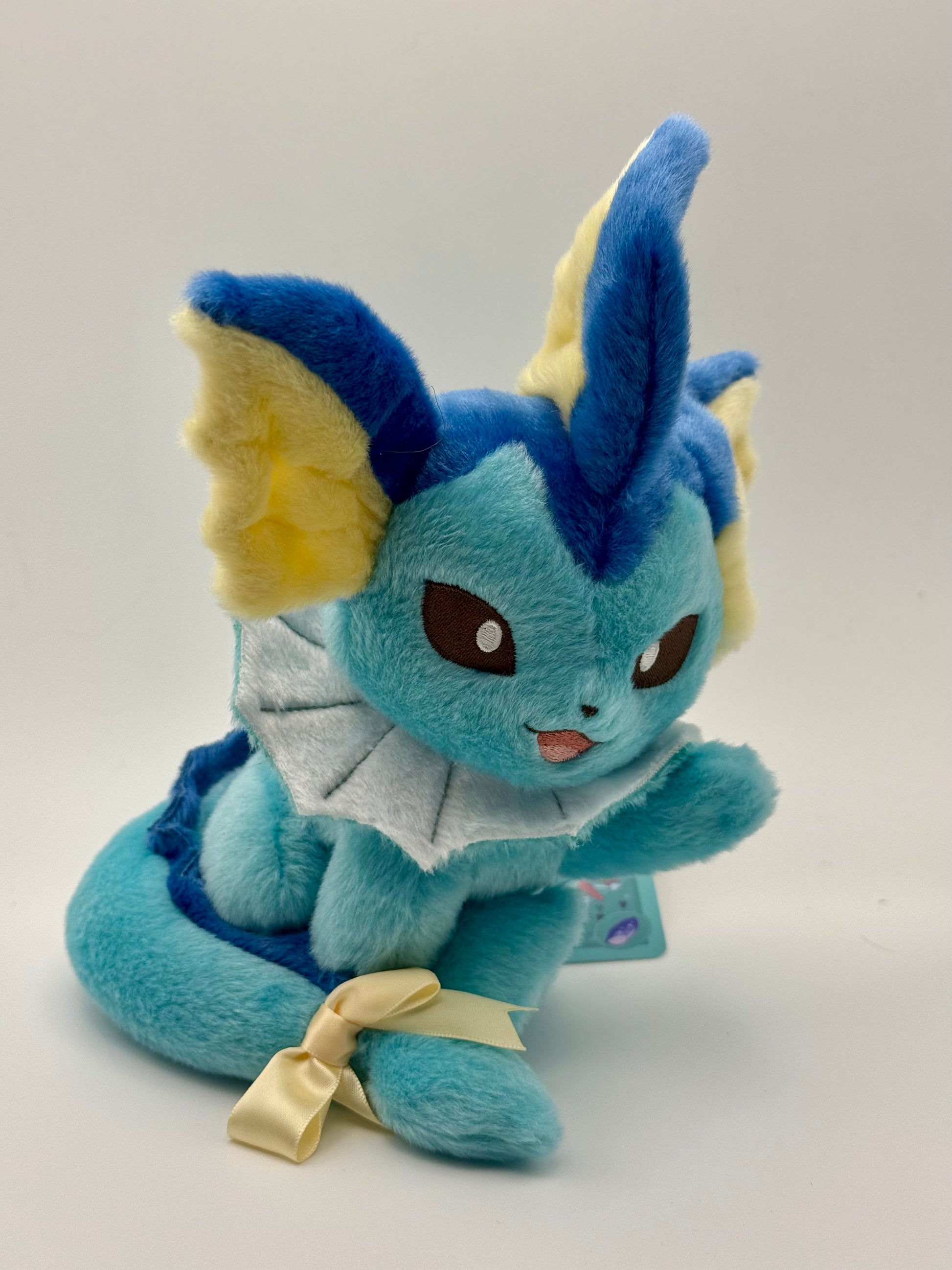 Eevolvd Vaporeon Plush med vinkande tass och sittandes med ett leende sedd framifran direkt fran Pokemon Center Japan