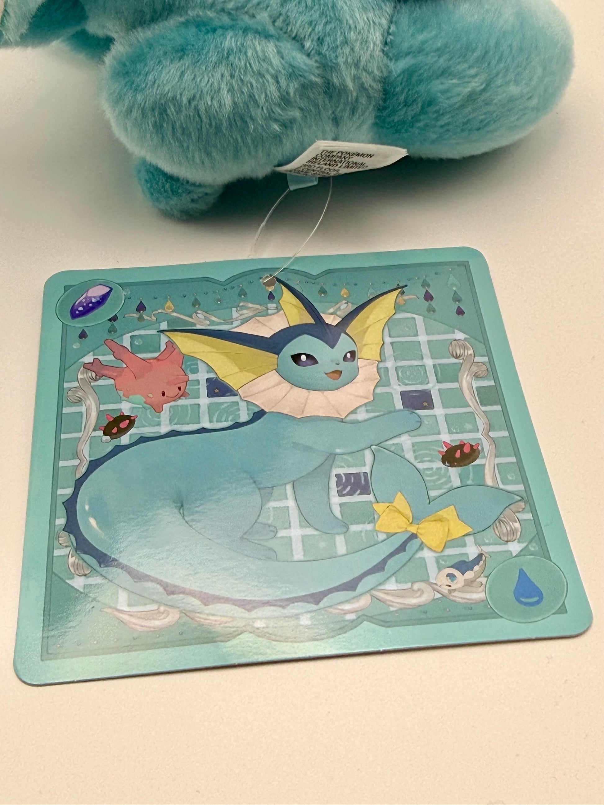 Eevolvd Vaporeon Plush med vinkande tass och sittandes med ett leende med sin tag framsida direkt fran Pokemon Center Japan